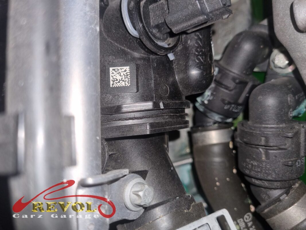 The thermostat housing on the engine, its QR data label visible, hoses connected.