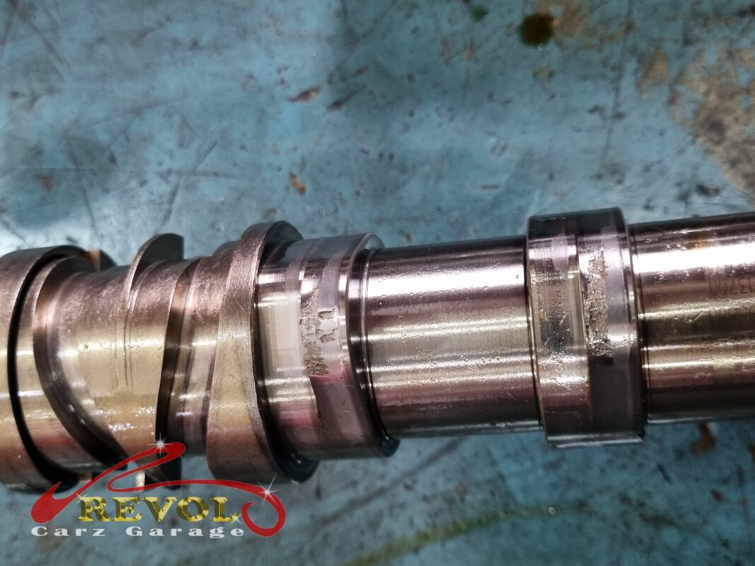 Close-up of the old camshaft, the worn and scored surface visible.