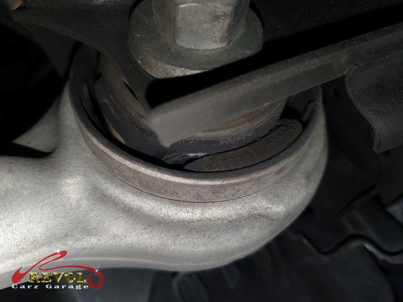 The worn front control arm bush with cracked, torn rubber.