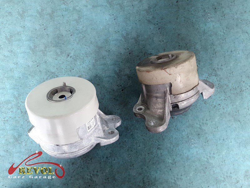 The worn engine mount with cracked and sunken rubber.