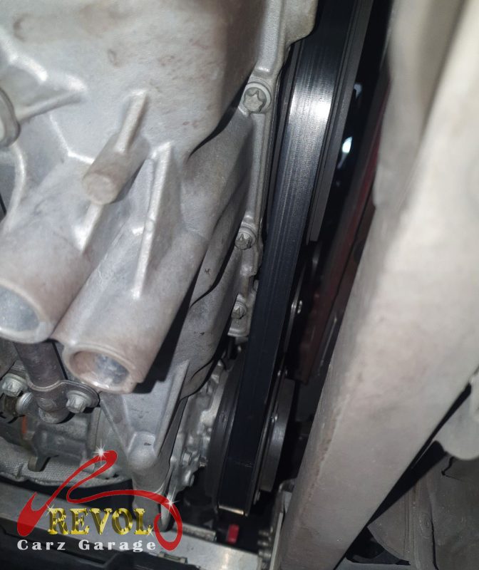 The old tensioner and idler pulleys removed alongside the belt.