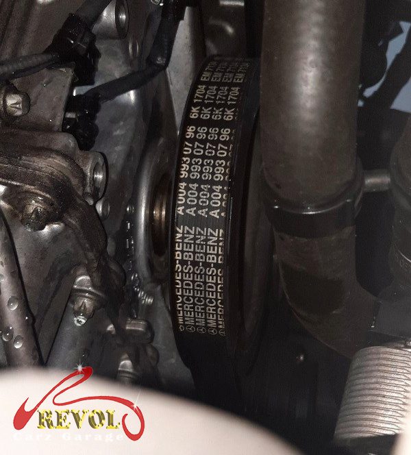 The old tensioner and idler pulleys removed alongside the belt.