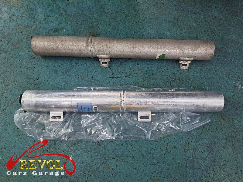 The old failed compressor removed alongside the new compressor and receiver-drier.