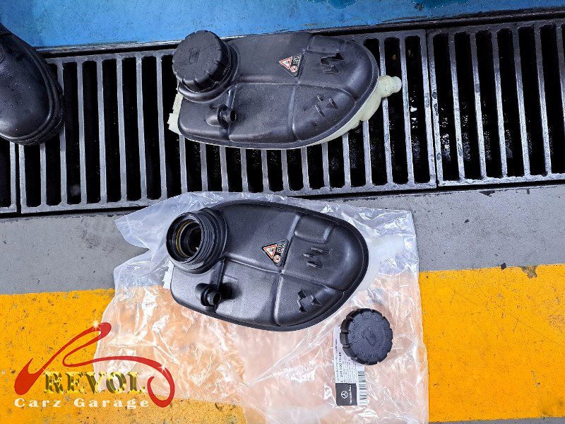 The old cracked coolant tank removed from the engine bay.