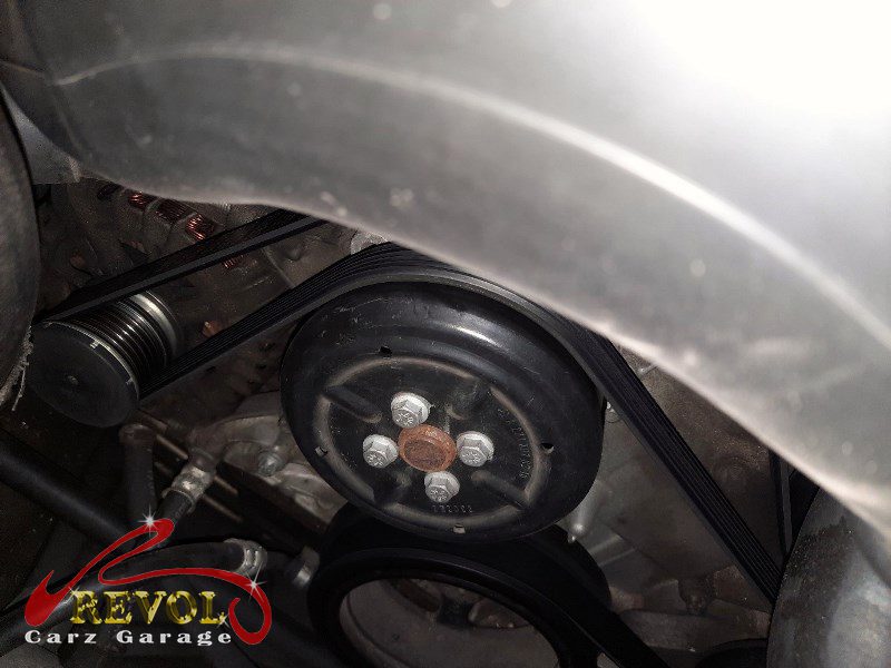 The old water pump and thermostat module removed showing the rough bearing.