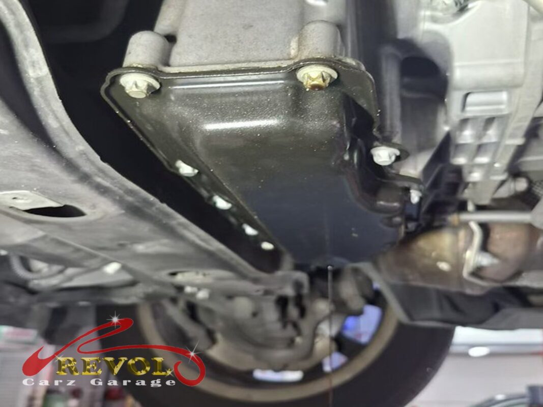 The lower steel sump pan under the car, oil residue marking the leak.
