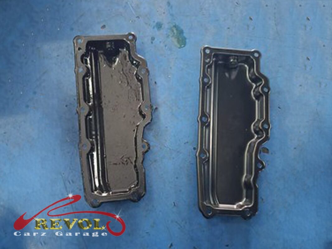 The old lower sump pan (left, oily inside) beside the new Mercedes-spec pan (right) with a fresh gasket.