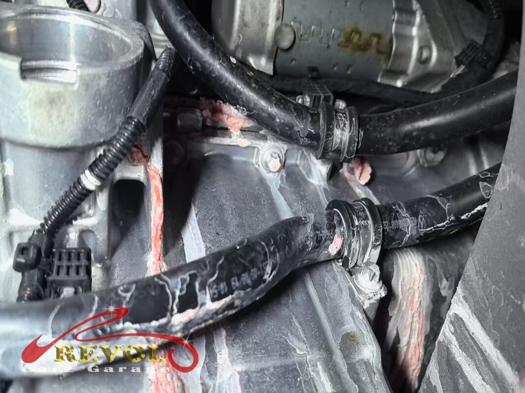 Dried pink coolant crusted around the thermostat housing in the engine bay, the trace of the crack.