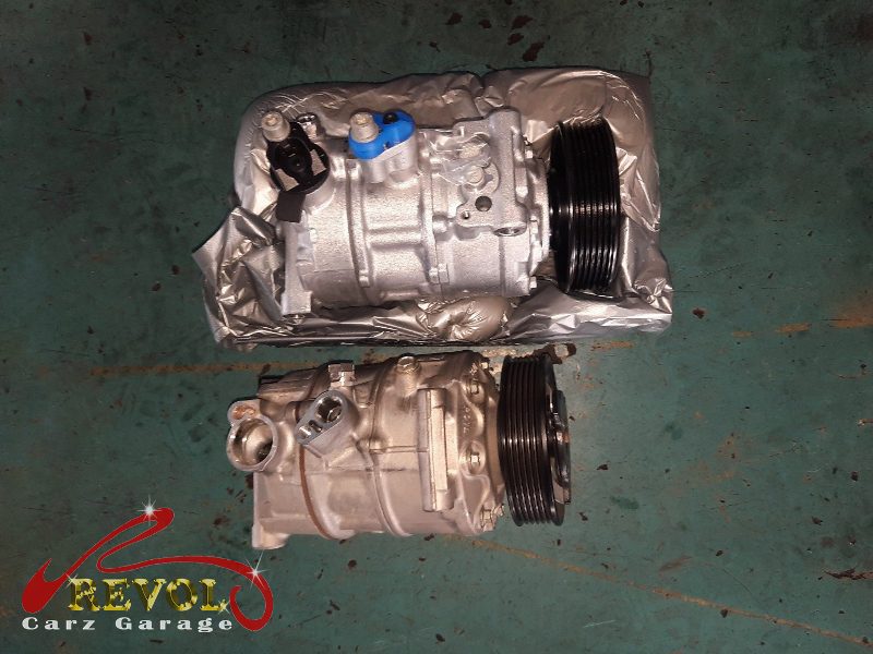 The old failed compressor removed alongside the new compressor and receiver-drier.