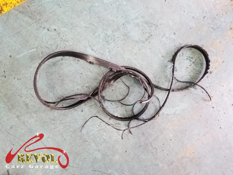 The old drive belt on the Volkswagen Jetta, hardened and cracked from its miles.