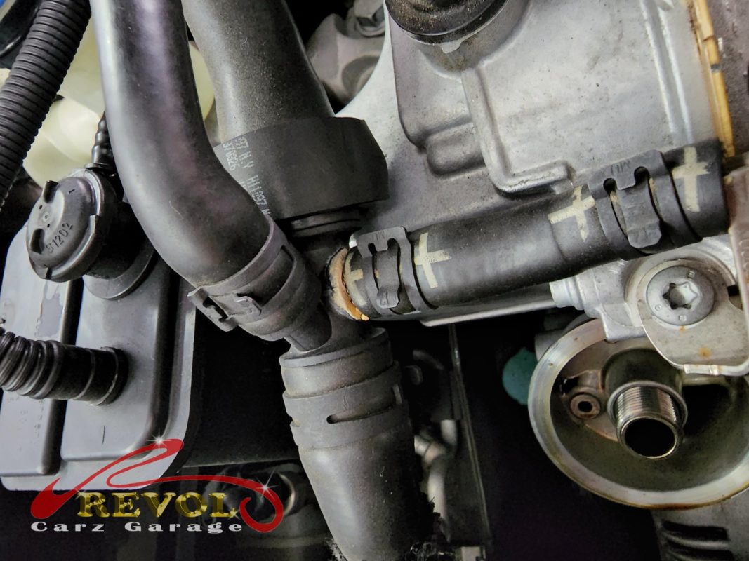 The old cracked plastic coolant connector removed from the engine.