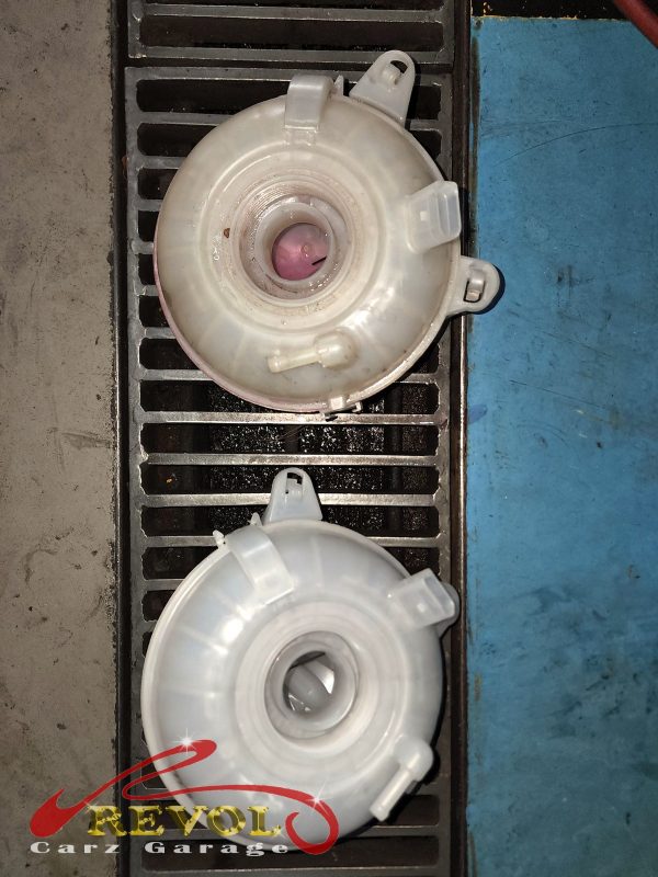 The old cracked coolant expansion tank removed from the engine bay.
