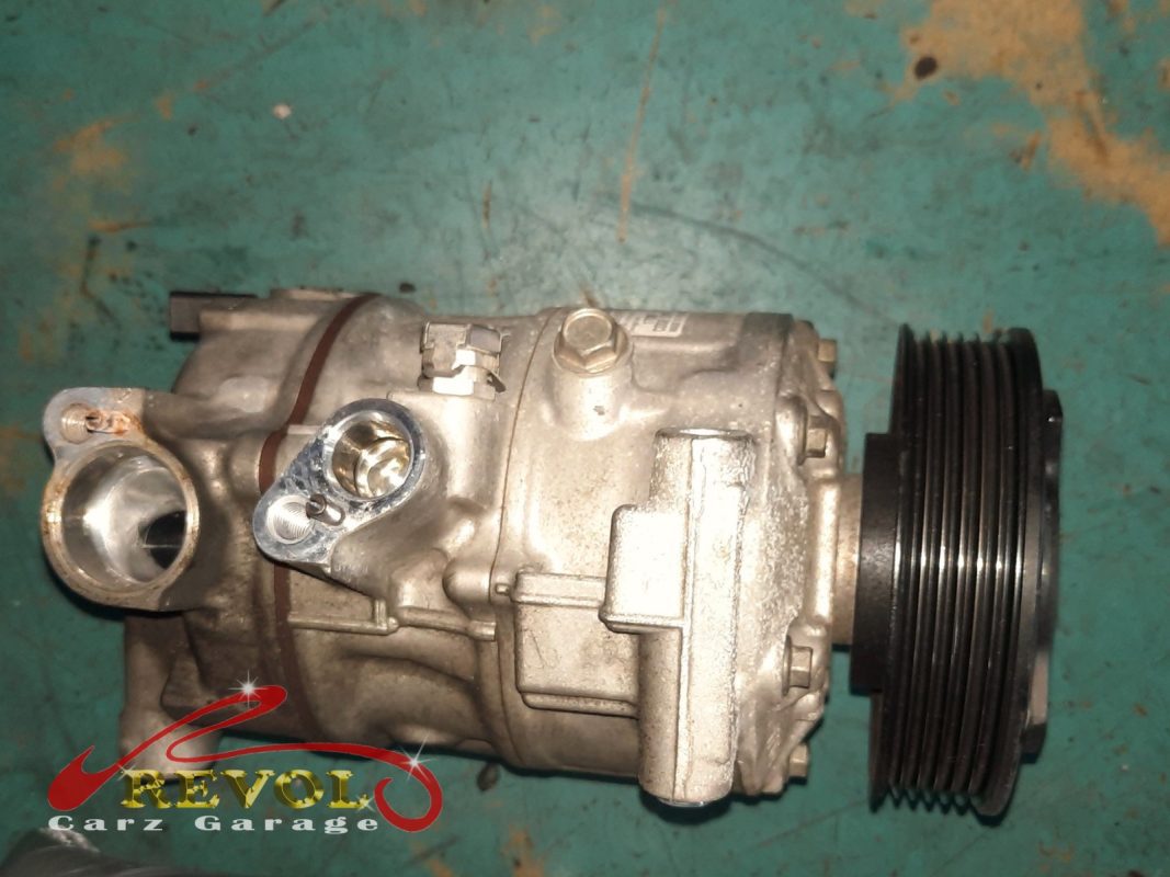 The old AC compressor removed from the engine.