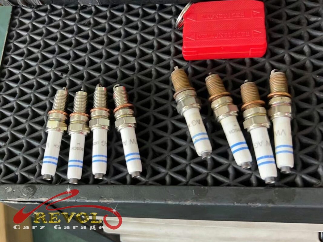 The old worn spark plugs beside the new VW-spec set, ready to fit.