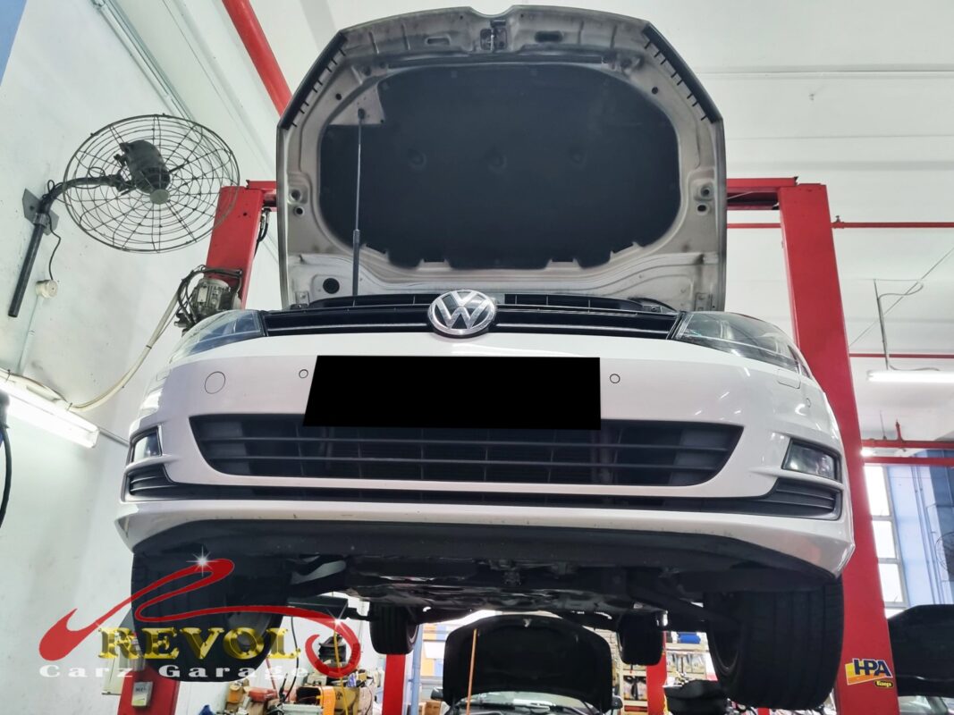 The old AC compressor removed from the Volkswagen Golf, oil weeping from the seal.