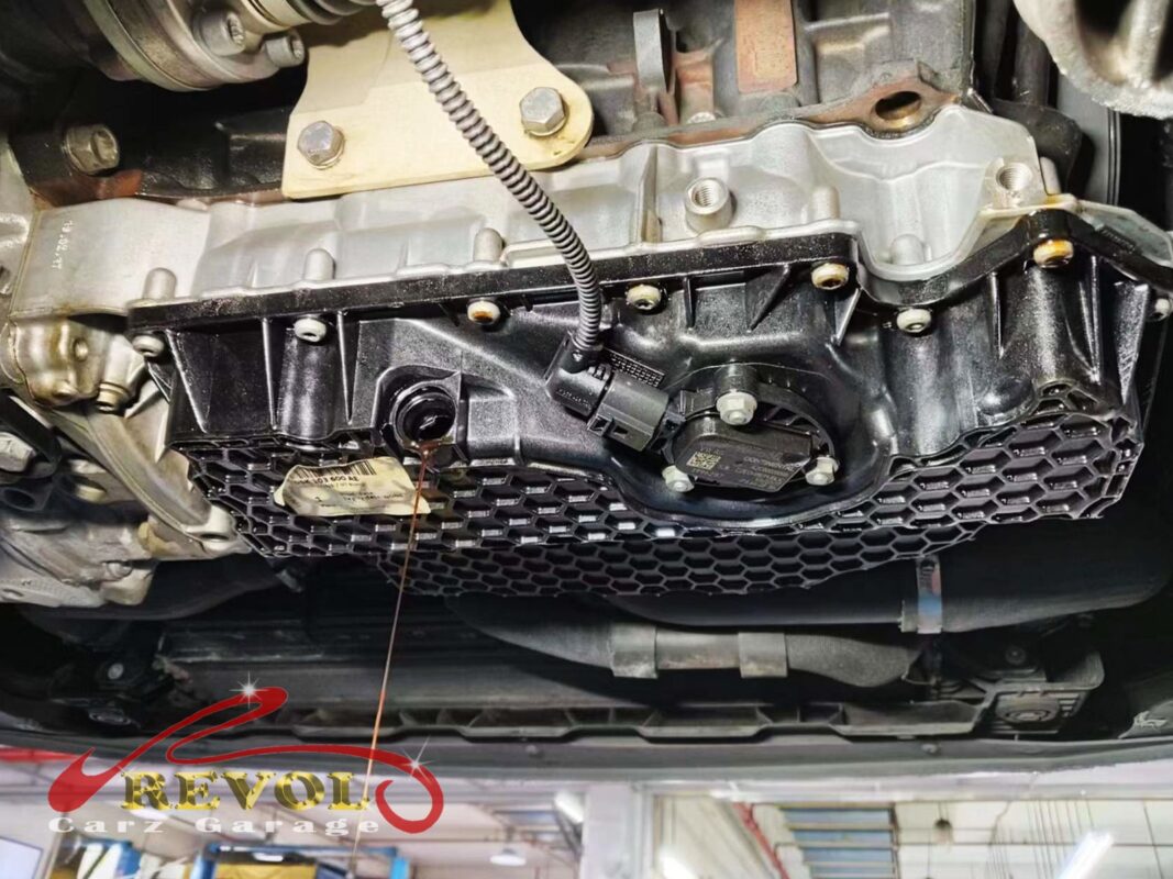 The lower oil sump pan exposed under the car, the leak being traced.