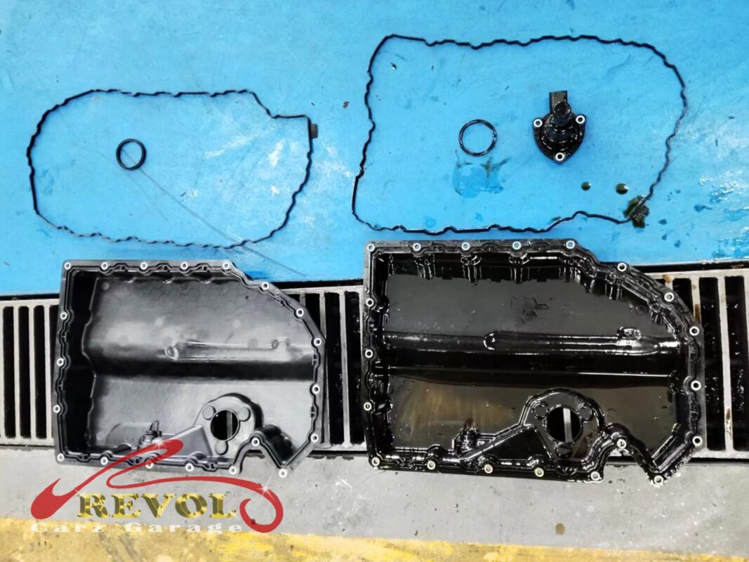 The old lower sump pan (left, oily) beside the new VAG-spec pan (right) with a fresh gasket and sensor.