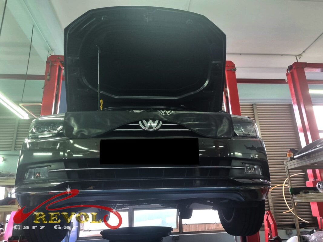 The Passat up on the two-post lift, hood open, in for the oil leak.