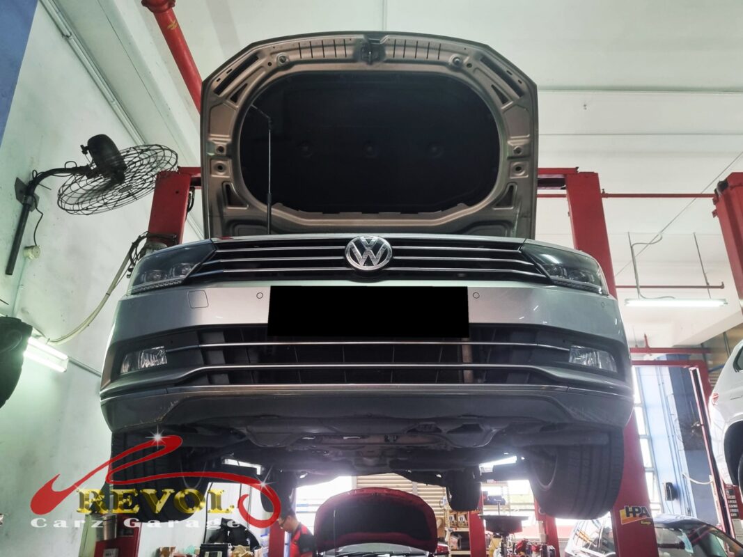 The Passat up on the two-post lift, hood open, in for the loose steering and the clunk.