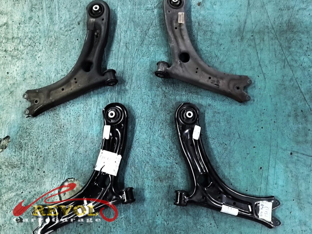 The old lower arms (top, grimy) beside the new VAG-spec pair (bottom).