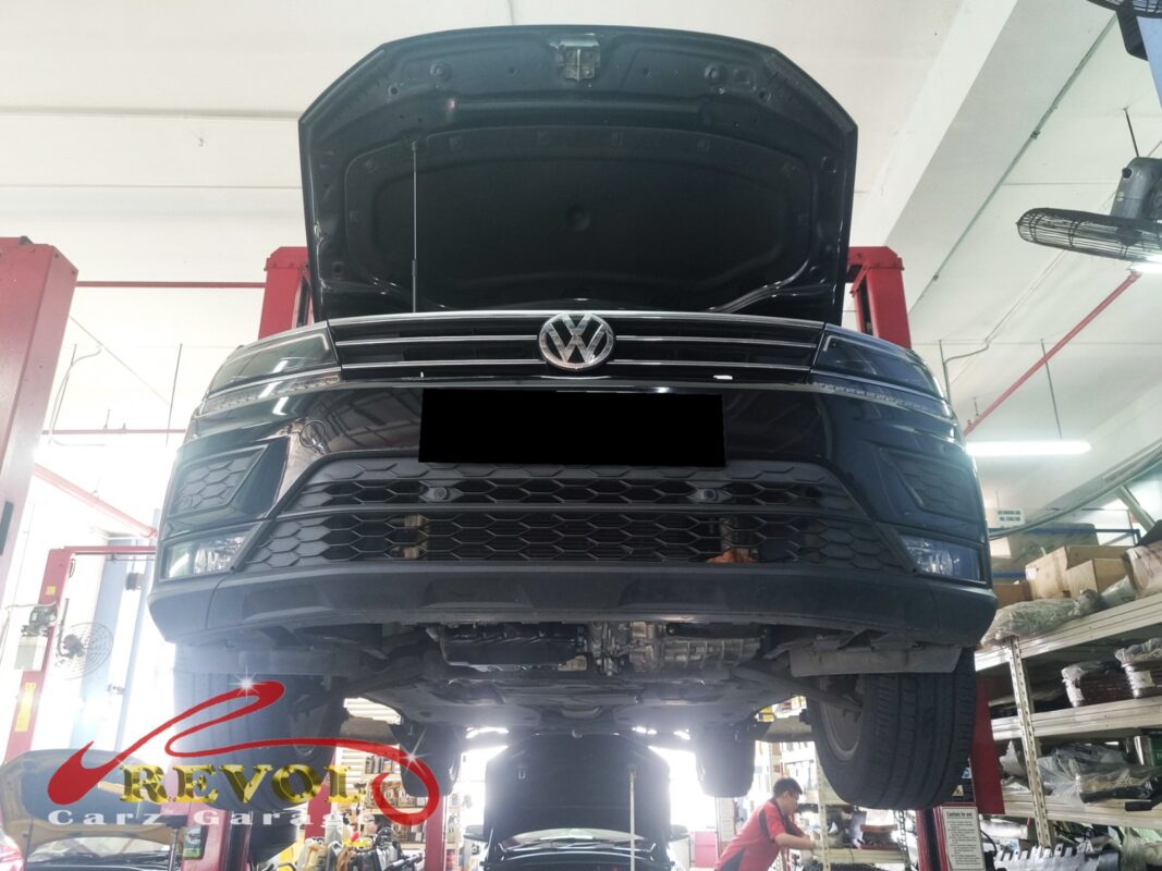 The Tiguan up on the two-post lift, bonnet open, in for the oil use, the blue smoke and the rough idle.