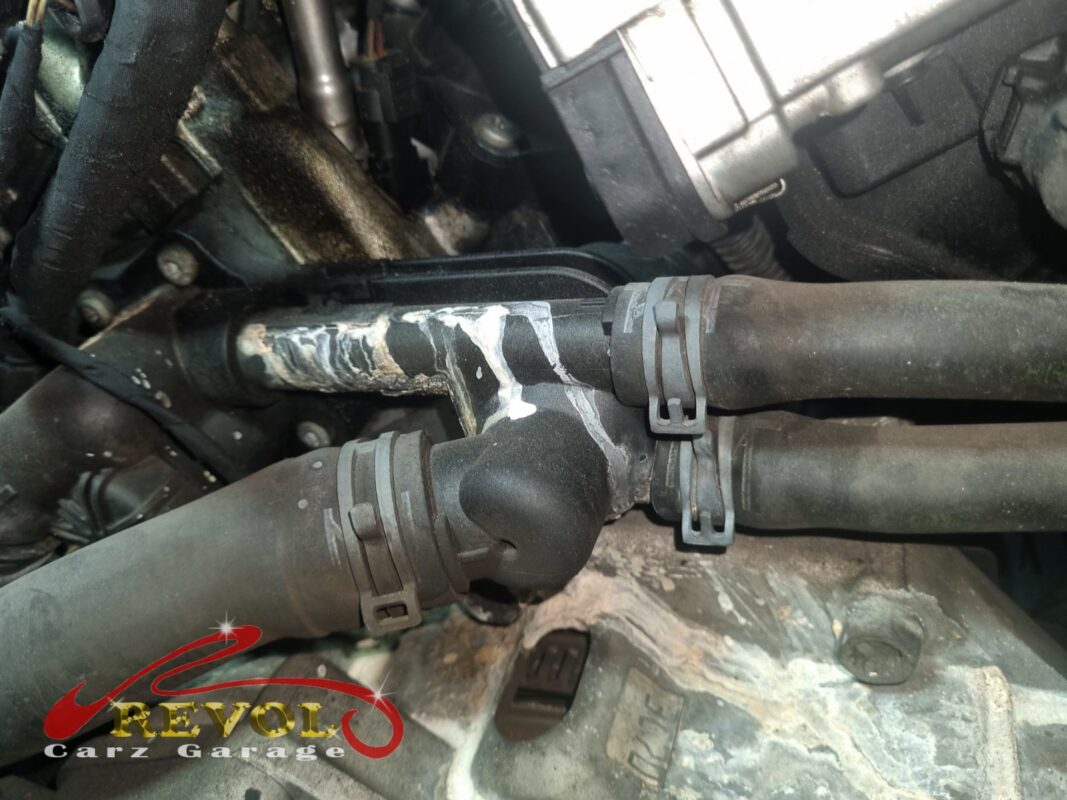Dried coolant deposits crusted around the housing and hose joints, the leak that brought it in.