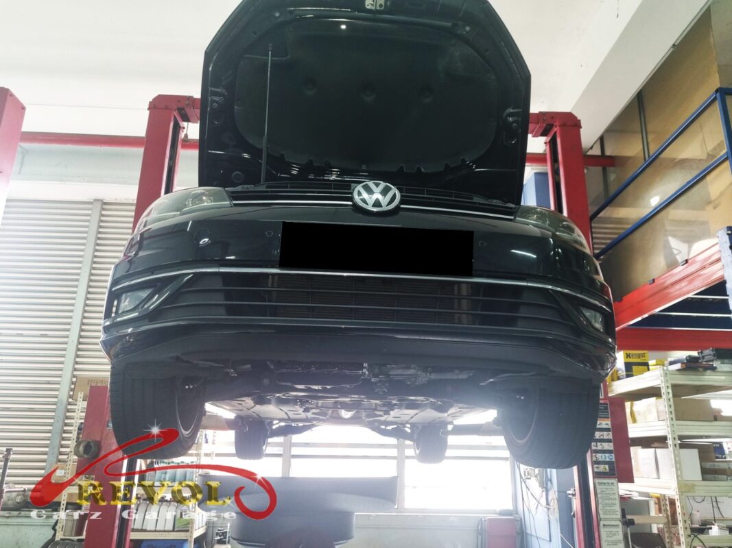 The Golf up on the two-post lift, bonnet open, in for the squeal, the pedal vibration and the brake-wear warning.