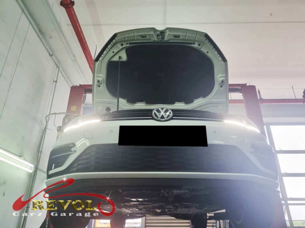 The Golf up on the two-post lift, bonnet open, in for the oil use, the greasy liner and the rough idle.