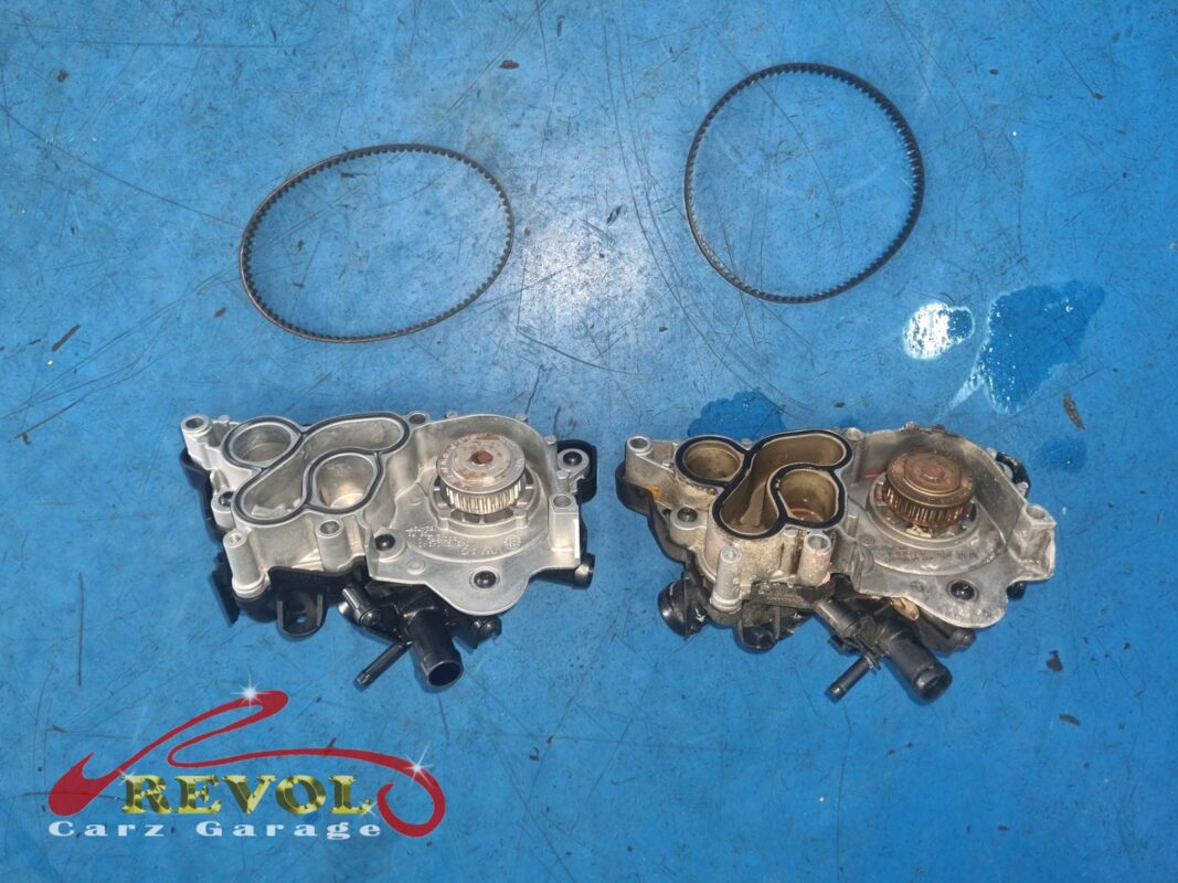 The old coolant pump (right, pink-stained) beside the new VAG-spec replacement (left), with the toothed drive belts.