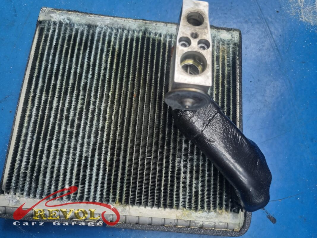 The old evaporator core out, fins grimed over, the expansion valve still attached.