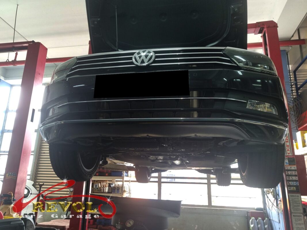 The Passat up on the two-post lift, bonnet open, in for the oil leak and the on-off misfire.