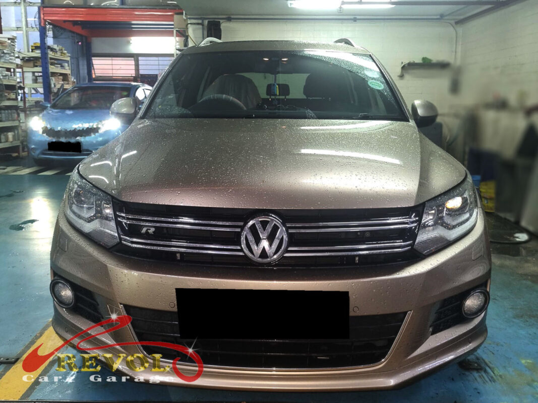 Volkswagen Tiguan on the workshop lift with both front wheels off for lower arm replacement.