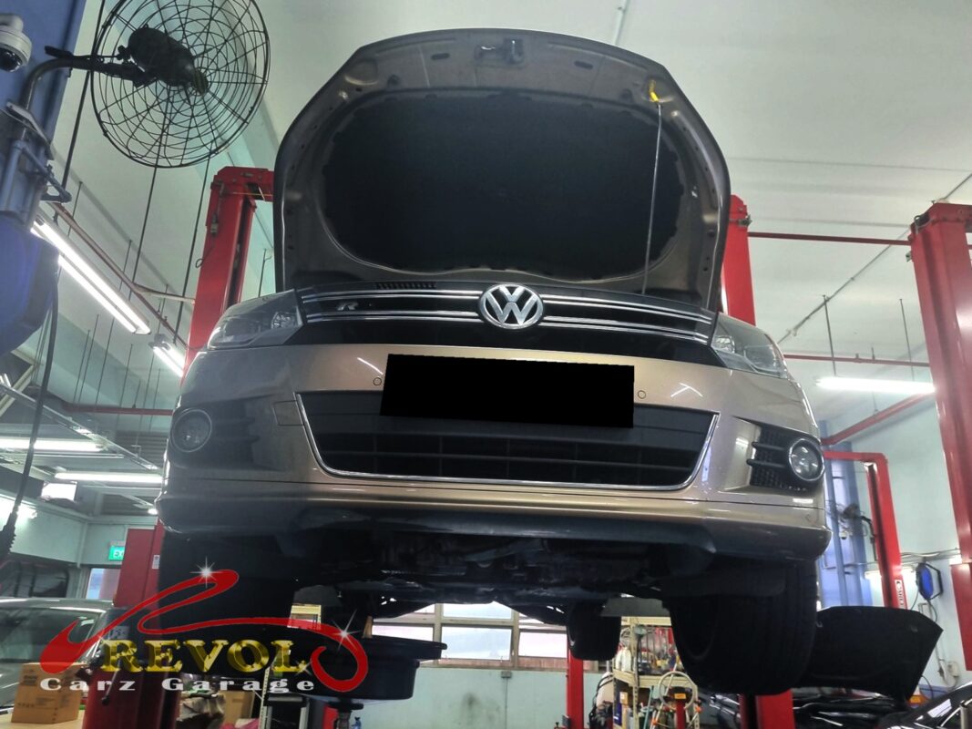 The Tiguan up on the two-post lift, bonnet open, in for the clunk and the vague steering.