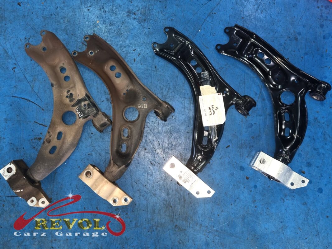 The two old lower arms (left, rusted) beside the new VAG-spec pair (right), with their rear bush brackets below.