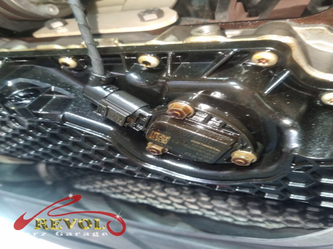 Looking up at the sump and the oil level sensor in its base, oil traces around the gasket line.