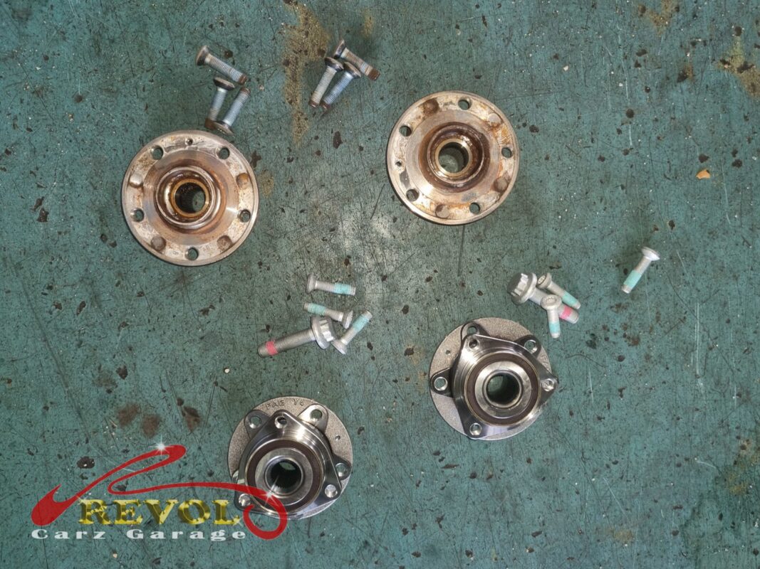 The old rear hub bearing units (top, rusted) beside the new VAG-spec replacements (bottom), with new bolts.