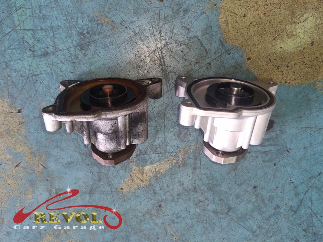 The old water pump (left, stained) beside the new VAG-spec replacement (right), with a fresh seal.