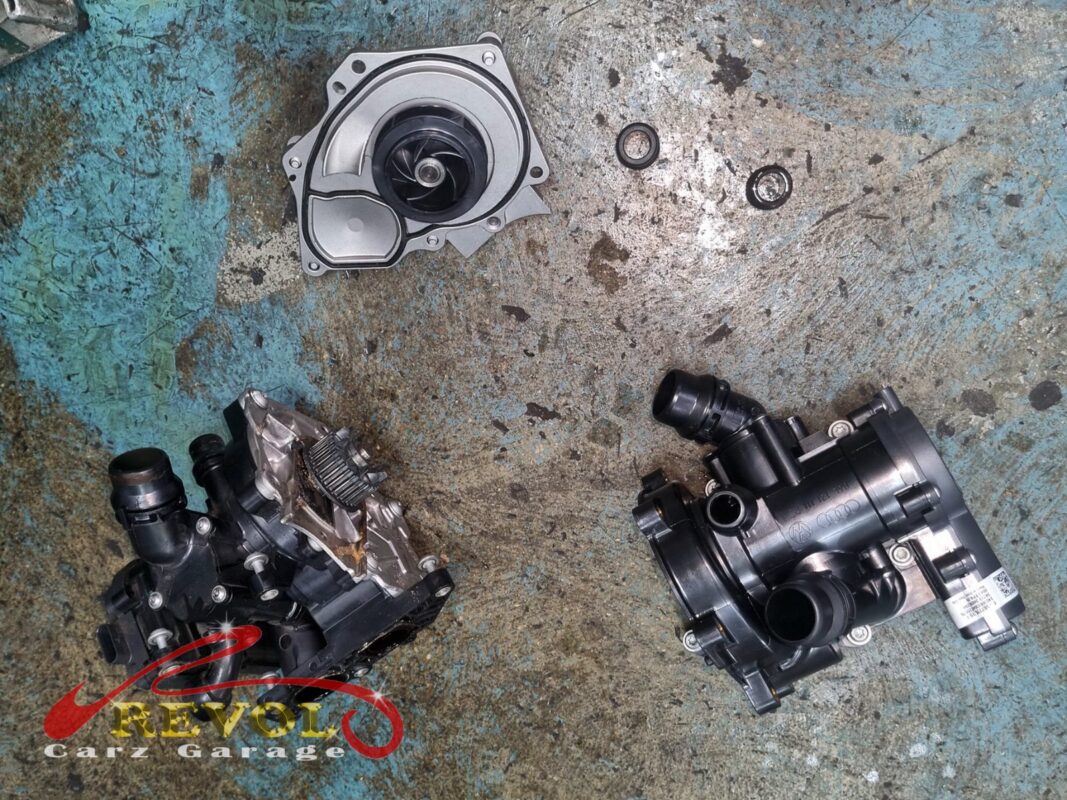 The old fouled module (bottom left) out, with the new VAG-spec water pump (top) and thermostat housing (bottom right) going in.