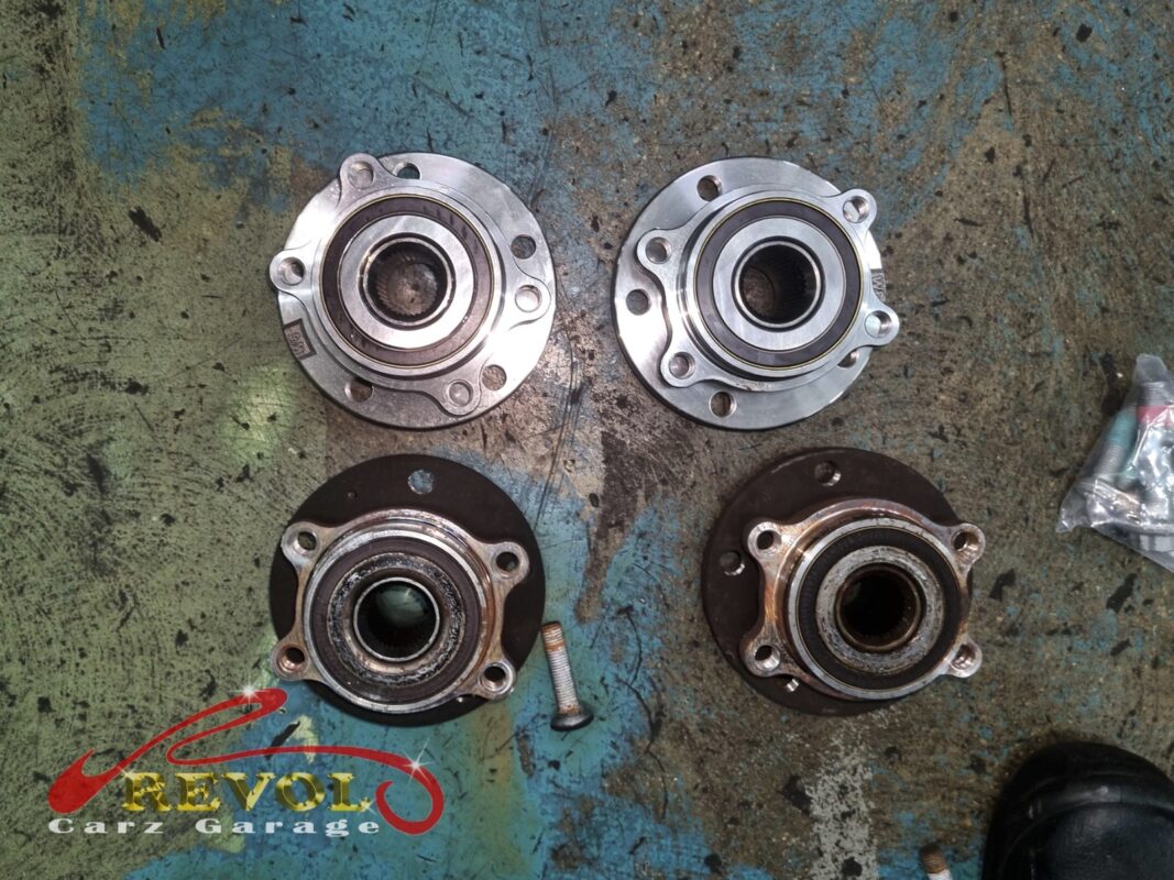 The old front hub bearing units (bottom, rusted) beside the new VAG-spec replacements (top).