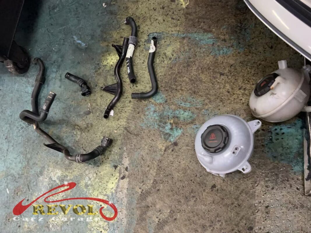 The old coolant hoses and the old expansion tank (right) off the car, beside the new VAG-spec tank (centre).
