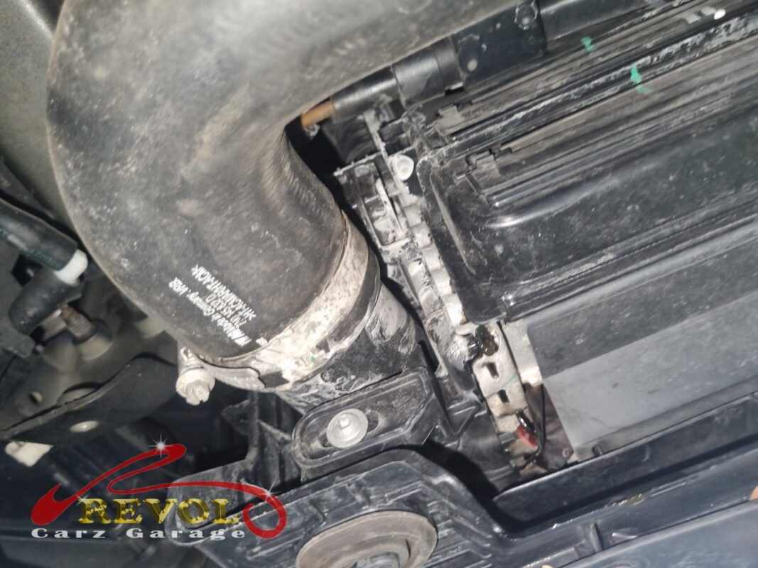 Dried coolant crusted along the radiator's top tank, the cracked seam that brought it in.