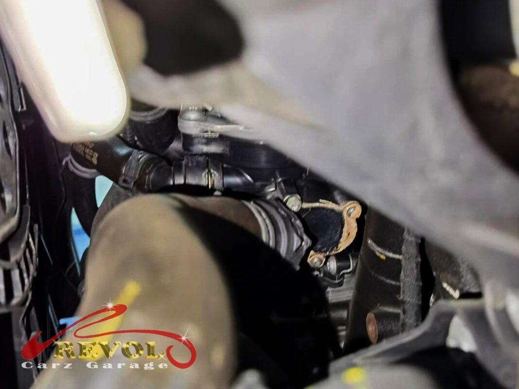 The water pump and thermostat housing area, coolant residue around the pump seal.