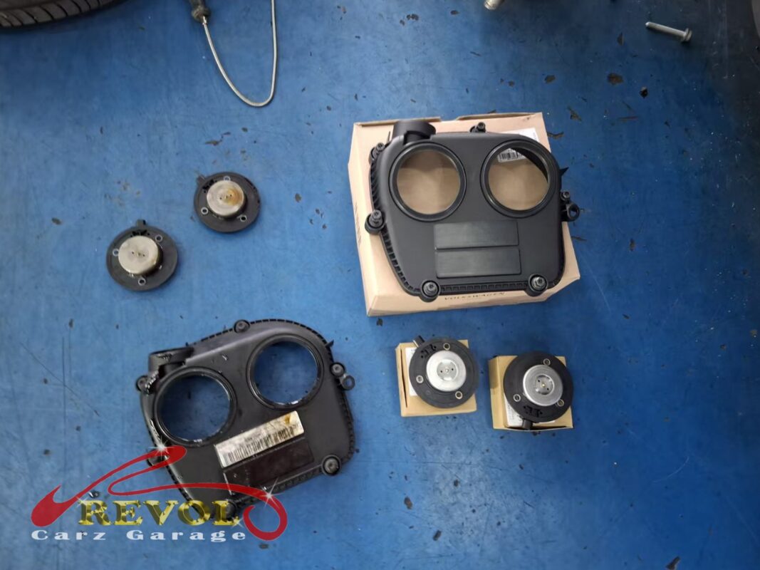 The old timing cover (bottom left) beside the new VAG-spec replacement (top), with fresh cam-end seals.