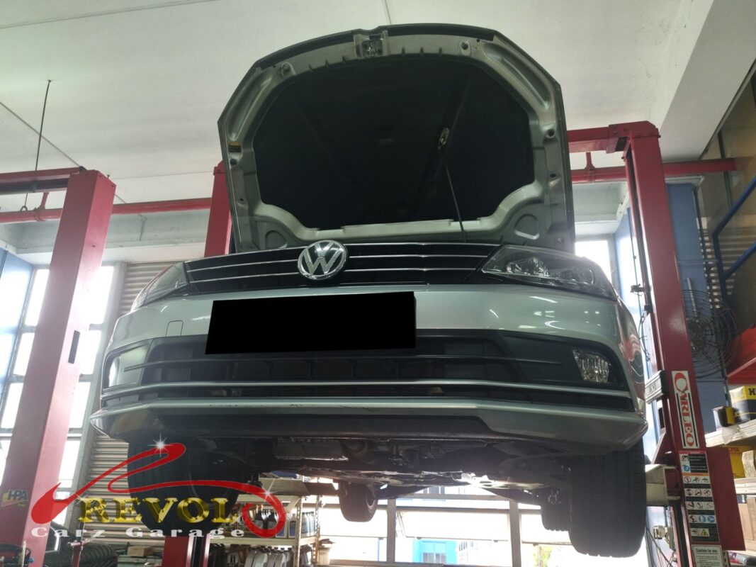 The Golf up on the two-post lift, bonnet open, in for the coolant leak and the slow warm-up.
