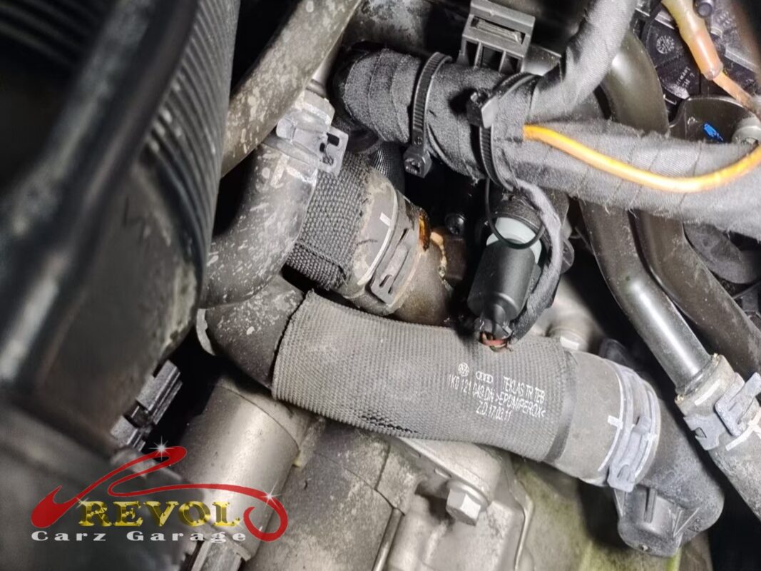 The corroded plastic connection on the thermostat housing, dried coolant around the crack.