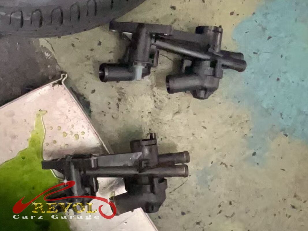 The old thermostat housing (top) beside the new VAG-spec replacement (bottom), integrated thermostat and all.