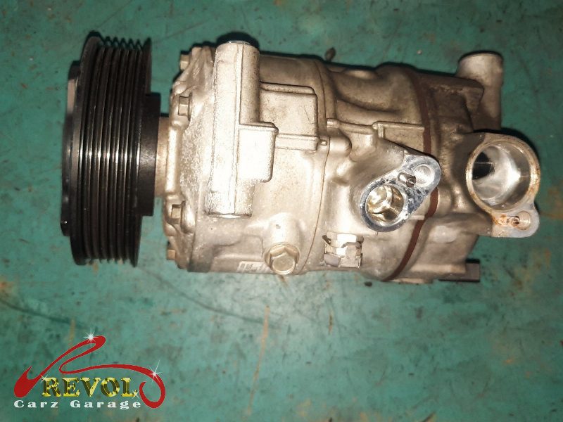 The old failed compressor removed alongside the new compressor and receiver-drier.