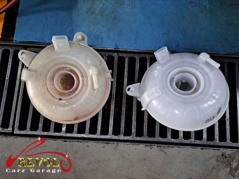The old cracked coolant tank removed from the engine bay.