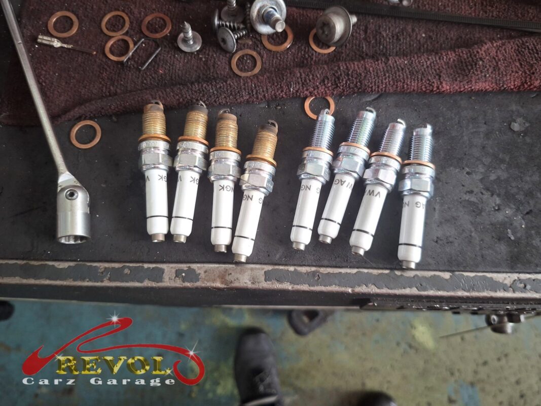 The four old spark plugs (left) beside the four new VAG-spec replacements (right), part of the service.