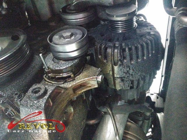 The failed alternator soaked in oil from a leak above it.